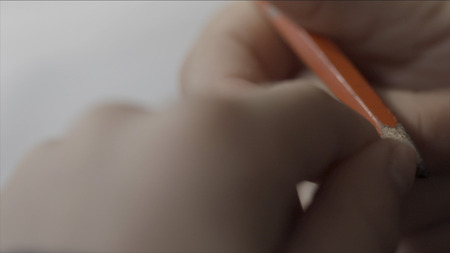 Man nervously twirls a pencil in your hand close up. Close up of hand holding a pencil. Fingers hold a pencil macro shoot. Mans hand holding a pencil to writing on paperの写真素材