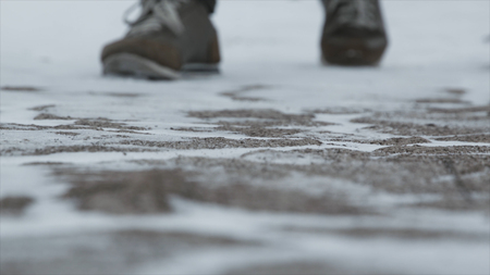 Close-up of male legs in winter shoes walking on snow. Footage, View of walking on snow with Snow shoes and Shoe spikes in winter. Mens legs in boots close up the snow-covered pathの写真素材