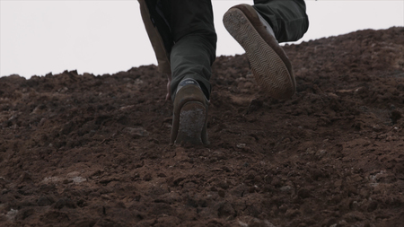 Close up of hiking boots and legs climbing up rocky trail. Close up climber legs make a last steps before peak. Close up of man foot in the moutain.の写真素材