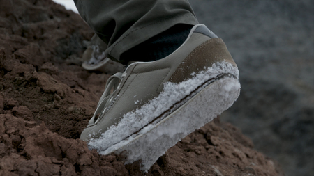 Close-up of hiking boots and legs climbing up the rocky trail. Man foot on the mountain.