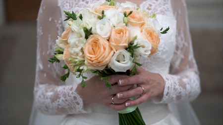 Nice wedding bouquet in brides hand. Clip. Fiancee in a beautiful white dress holding a beautiful bouquet of wedding flowers made of tender roses in handの写真素材