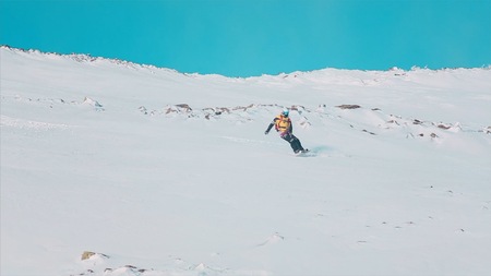 Happy snowboarder having fun snowboarding backcountry on a sunny winter day in snowy mountains. Video. Extreme freeride snowboarder riding fresh powder snow off piste in mountain ski resortの写真素材