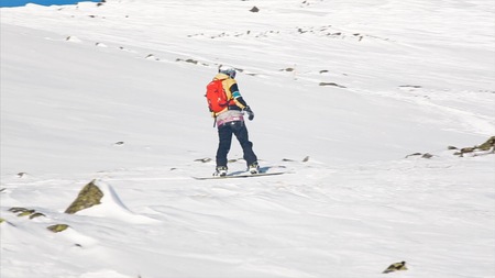 Happy snowboarder having fun snowboarding backcountry on a sunny winter day in snowy mountains....