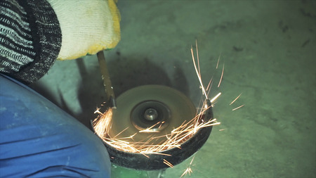 Manual sharpening and cutting of metal by grinding machine. Clip. Sharpening metal on a grinding discの写真素材