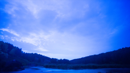 Lake at night - timelapse. Video. Night sky timelapse with running stars. A view of the stars of the Milky Way with a silhouette of a pine trees forest near a lake in the mountain. Falling stars reflection in the water.の写真素材
