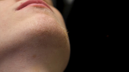 Close-up side view portrait of young bearded man getting beard grooming in modern barbershop in slow...