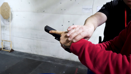 Man shoots at the shooting range with the instructor. Man trains shooting at shooting range. Man...