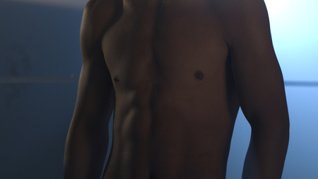 Half-length portrait of nude boxer with hands on hips, on dark background with light, close up. Young handsome male fighter standing concentrated before fight with putting palms togetherの写真素材