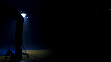The film crew works on creation of a videoclip. Gaffer prepares diffusion for a light in the studio....