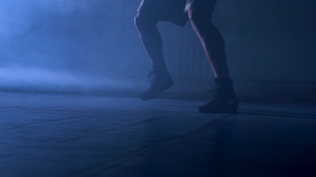 Bottom view of fighter training in the gym with smoke and light background. Silhouette of strong male boxer on dark background. Close up of athlete or sportsman moving fast while trainingの写真素材
