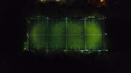Football players running around the football field. Night workout. Preparation for the match. Aerial...
