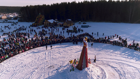 Moscow, Russia - February 26, 2018: Aerial view of Traditional burning of Maslenitsa Scarecrow. Burning of Scarecrow. Aslenitsa celebration. Man sets fire to a big doll-scarecrow on a stage in a city parkのeditorial素材
