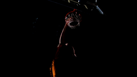 Close up of a basketball dunk. Throw in a basketball hoop on the background of yellow spotlights,の写真素材