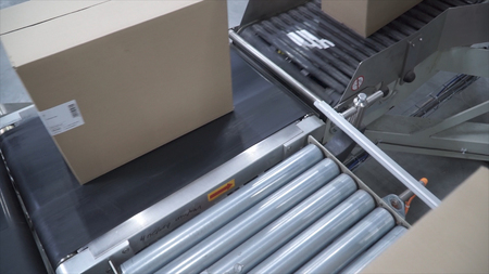 Cardboard boxes on conveyor belt in factory. Clip. Cardboard boxes on conveyor belt in distribution warehouse.の写真素材