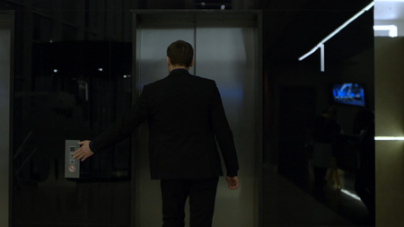 Man in business suit standing near the elevator, view from the back. Stock. businessman standing at...