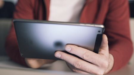 Young student sitting at desk interact with tablet computer and reads books. Stock. Education. Universityの写真素材