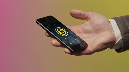 Business, technology and cryptocurrency concept - close up of male hand holding smartphone and...