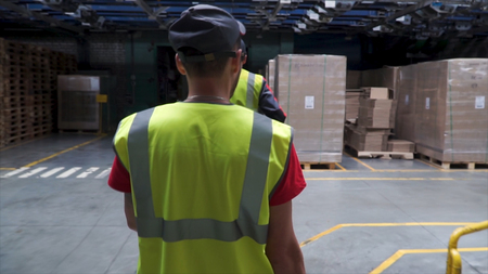 Back view on the male worker in yellow vest walking in the industrial facility. Clip. Following Shot...