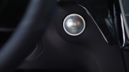 Driver hand pushes engine start stop button. Stock. Modern luxury crossover car interior details.