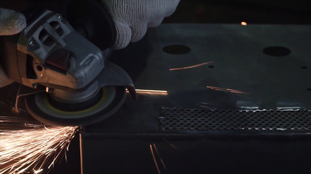 Man grinds a metal sheet. Clip. Grinding machine on work and spark movement in the automotive parts...