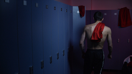 Disappointed and tired sportsman in semi lit locker room. Sad athlete in the locker room after the defeat at the tournament.の写真素材