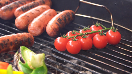 Juicy sausages and grilled vegetables on grill. Dinner outdoors. Garden party.の写真素材