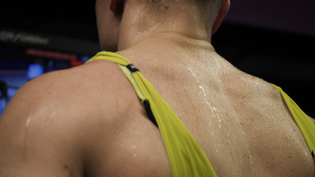 Athlete running on race track. Wet back of athlete running on a treadmill in gym
