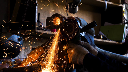 Close-up of worker cutting metal with grinder. Frame. Sparks while grinding iron. Circular cutting...