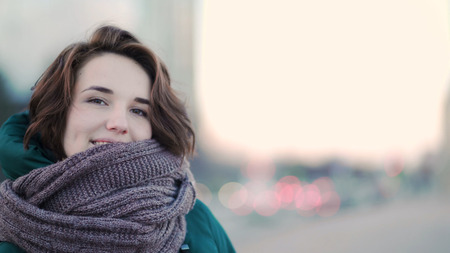 Beautiful cute young woman with a scarf on the street on background city. Urban styleの写真素材