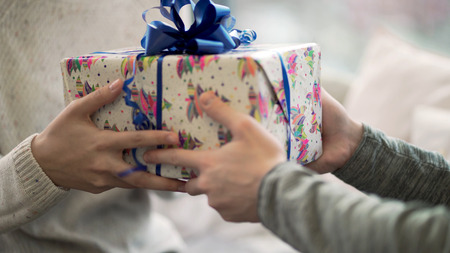 Close-up of man passes gift to woman. Close-up guy gave his girlfriend Christmas or new years gift. Festive winter atmosphereの写真素材