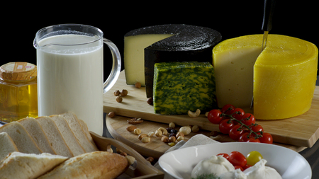 Still life in the old style with a jug and a mug of milk, a heads of cheese, toast, honey and eggs...