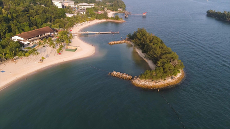 Coast of the small island near the equator line with beautifull forest along the shore and blue water. Shot. Seascape of a small beautiful island in the sea with palm trees and rocksの写真素材