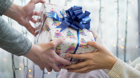 Give gift. Close up hands of couple in love giving a gift box . Happy relationship in outdoor scene....