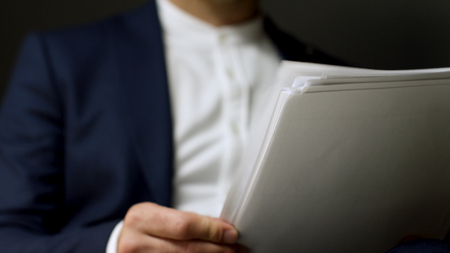 Extreme close up for a man during reading contract and turning the page, isolated on grey...