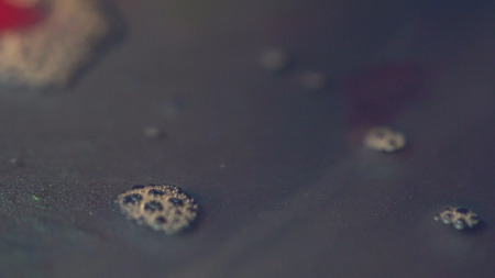 Close-up of dark water with glitter. Water mixed with powder glitter settled on bottom and on surface float small bubbles.の写真素材