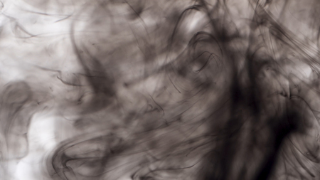 Close-up of black ink in water on white background. Drops of black ink beautifully splash in water, creating abstract art background.の写真素材