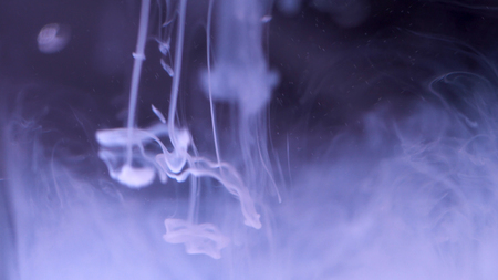 Ink splash in water. Close-up of abstract background of white ink falling into water on black background. Effect of moving smoke or fog mind.の写真素材