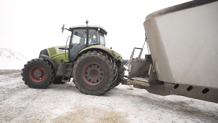 Close up for moving tractor with trailer at the farm in winter, agriculture concept. Footage....