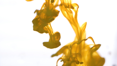 Close up for colored ink spreading in water on white background. Colorful, yellow abstract smoke falling from top to down.の写真素材