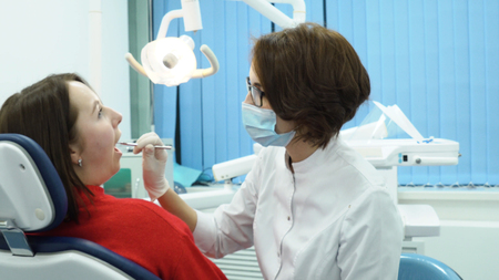 Woman dentist talking to patient. Media. Dentist woman consults patient about treatment before starting workの写真素材