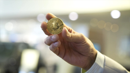 Businessman hand holding glowing bitcoin sign. Stock. Virtual money concept and Financial growth...