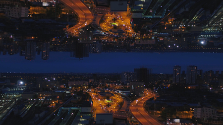 Aerial night view of a big city and beautiful lights, night life concept, mirror horizon effect. Media. Night cityscape with lighted roads and moving cars, inception theme.の写真素材