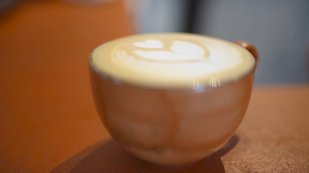 Close-up of cup with coffe and pattern. Art. Cozy and fragrant coffe mug with heart pattern of cream...
