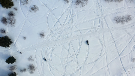 Top view of riding snowmobiles. Footage. Top view of two snowmobiles driving in circle leaving...