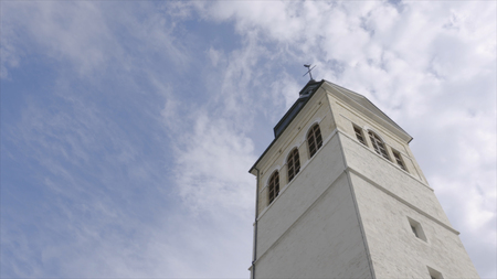 Church tower on a sunny day. Action. White Church steeple on background of blue skyの写真素材