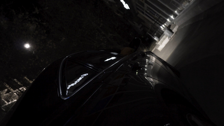 Close up for black car parked in the city at night with different shining lights, night life...