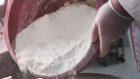 Pouring flour from the plastic container to the metal vat, food preparation concept. Stock footage. Close up for putting white flour to the metal bowl.の写真素材