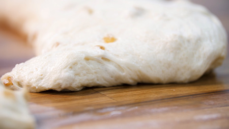 Close up view for raw pieces of pastry lying on the wooden board on the table. Stock footage. Traditional delicious pastry pieces with raisins ready for baking.の写真素材