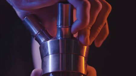 Close-up details of hookah. Action. Mens hands collect and twist details of hookah base on black isolated backgroundの写真素材