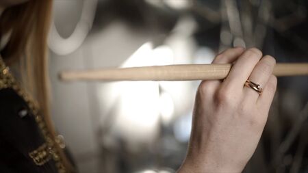 Close-up of hand with drumstick. Action. Female hand professional drummer holds wooden drumstick before playing at music rehearsal.の写真素材